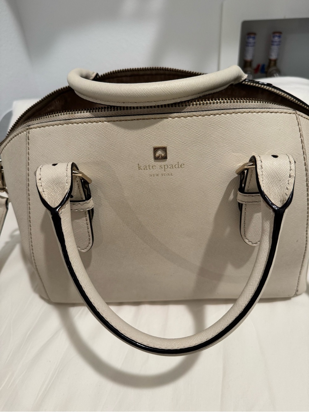 kate spade cream satchel with black trim and gold logo